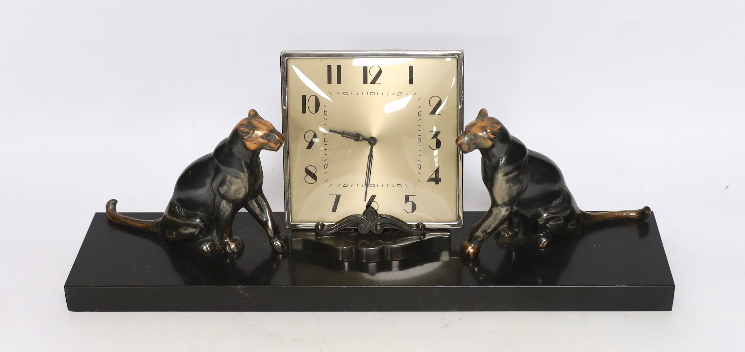 A patinated spelter Art Deco clock surmounted with two panthers, 40cm high